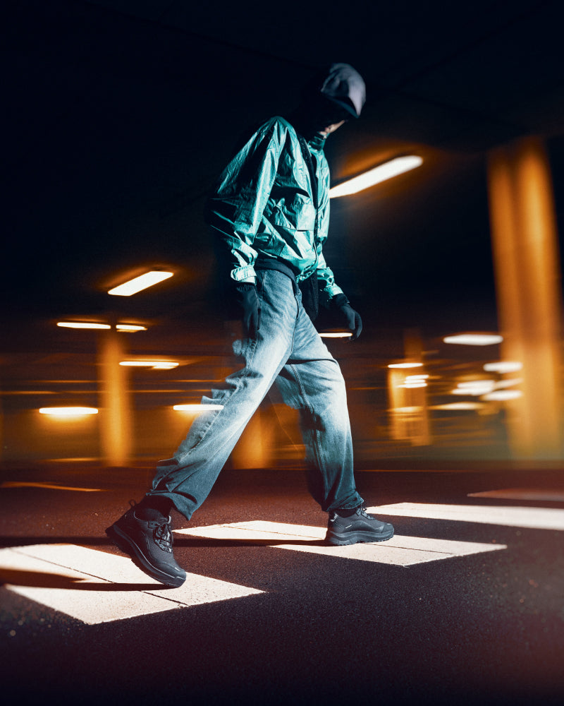 Mann med hette går på kveldstid over gangfelt med Gaitline sko på beina